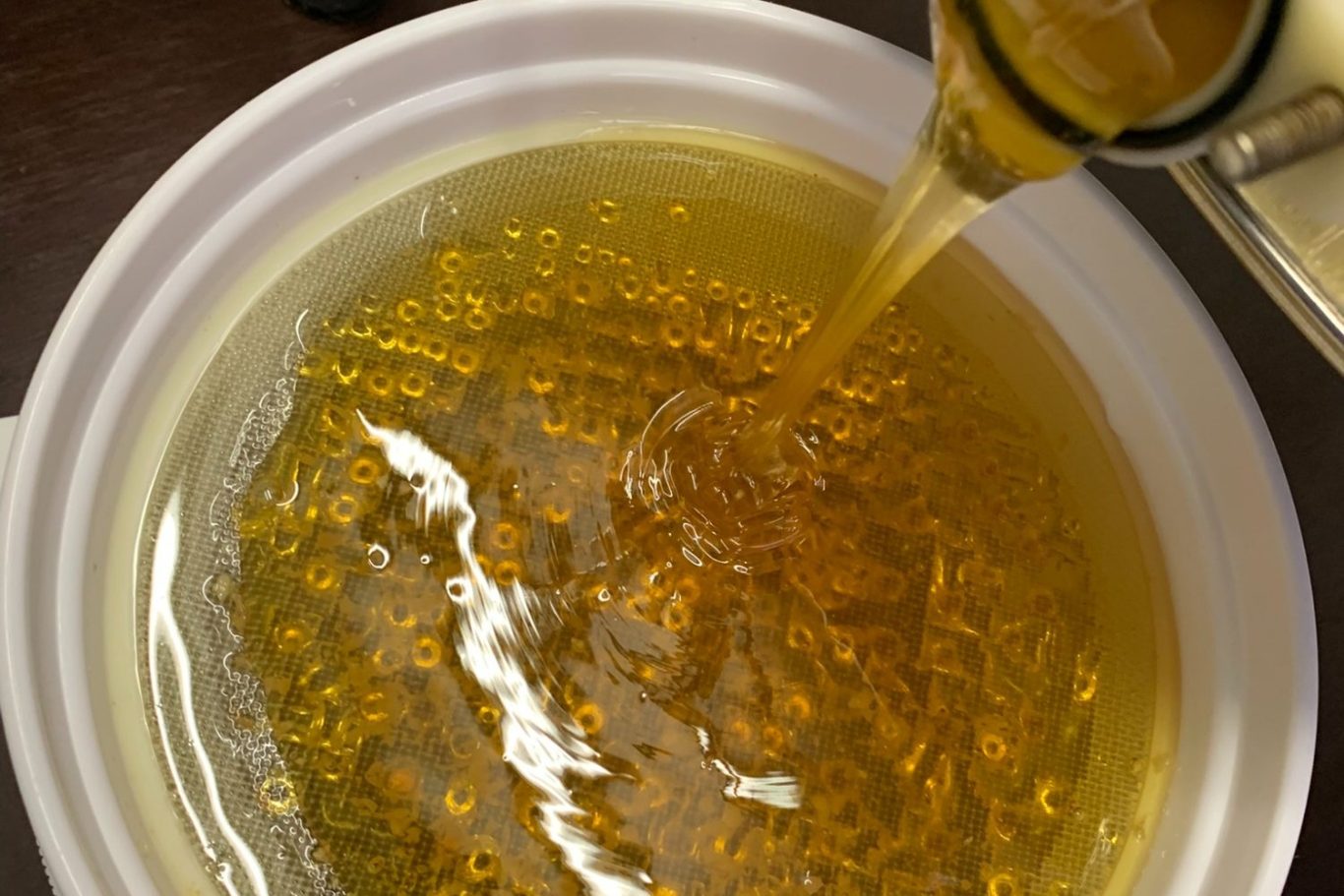 Traditionelle Honogschleuder Honigschleuder mit rotem Handantrieb in einem warm beleuchteten, rustikalen Raum.